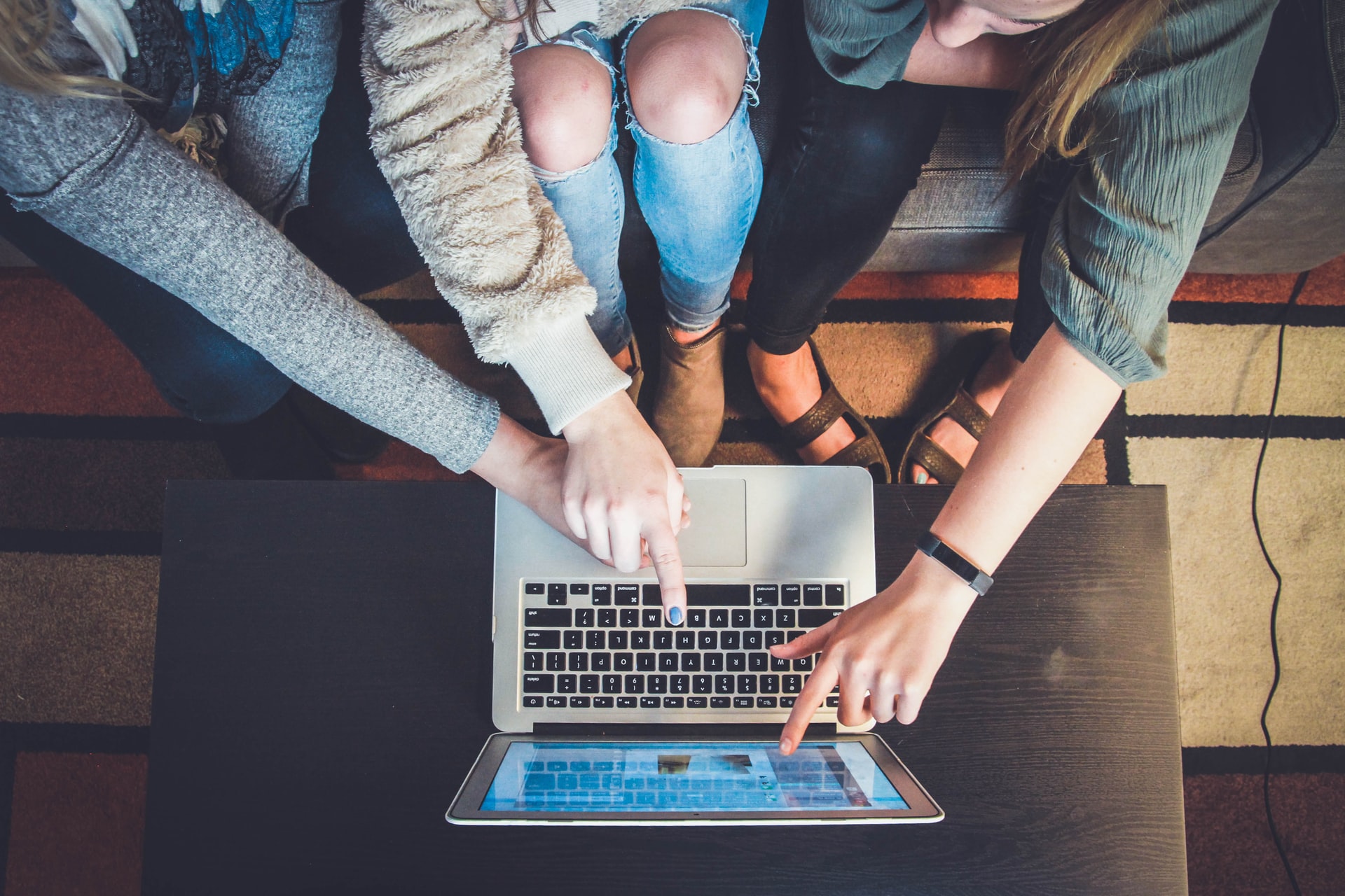 Three women sitting in front of a laptop pointing at the screen
